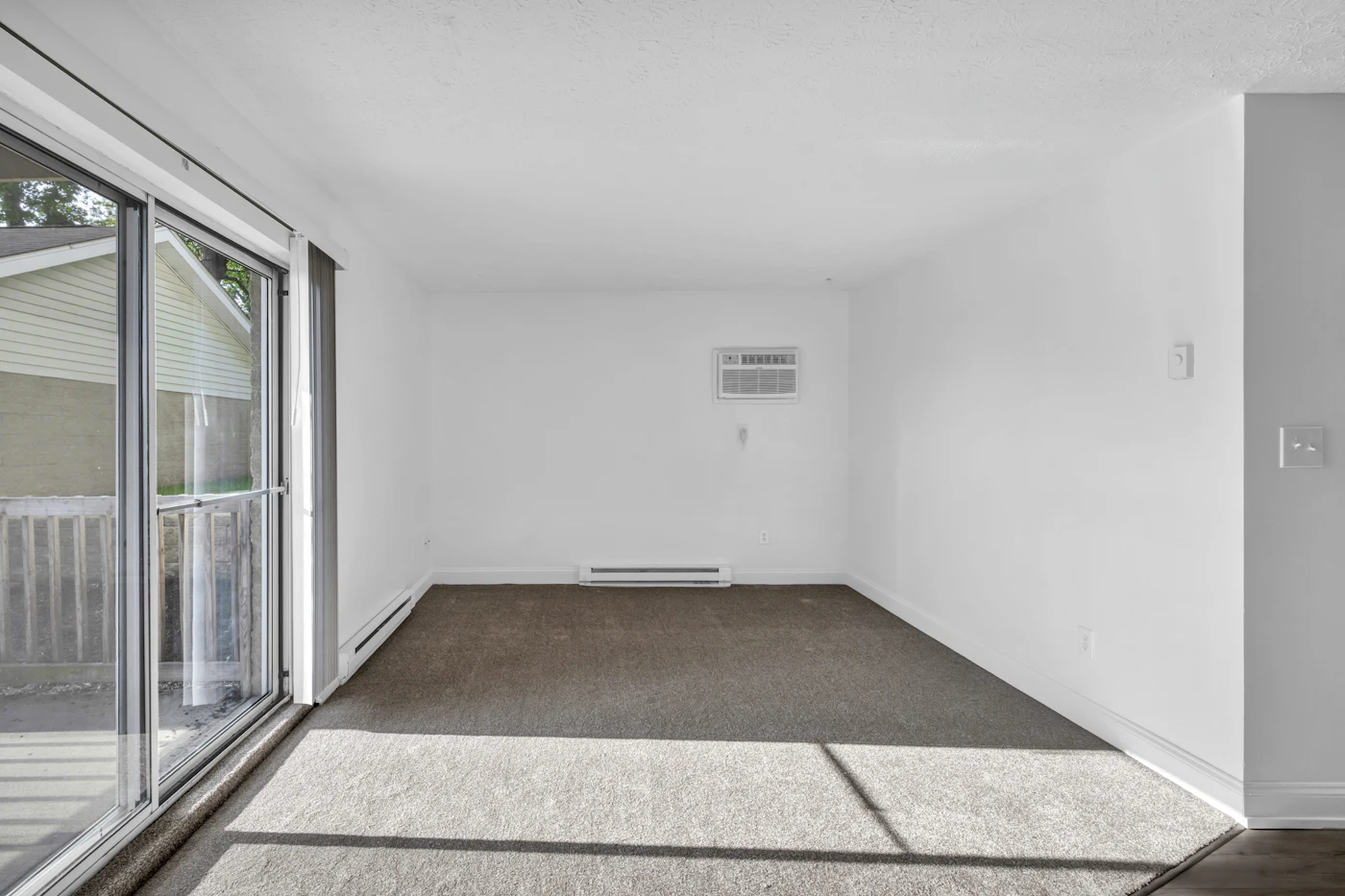 An empty condo bedroom with flattened, dated beige carpet and marks where the furniture stood